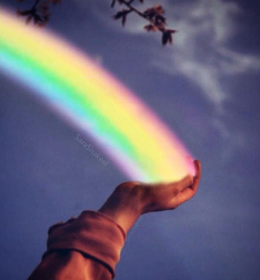 the end of a rainbow being held in the palm of someones end